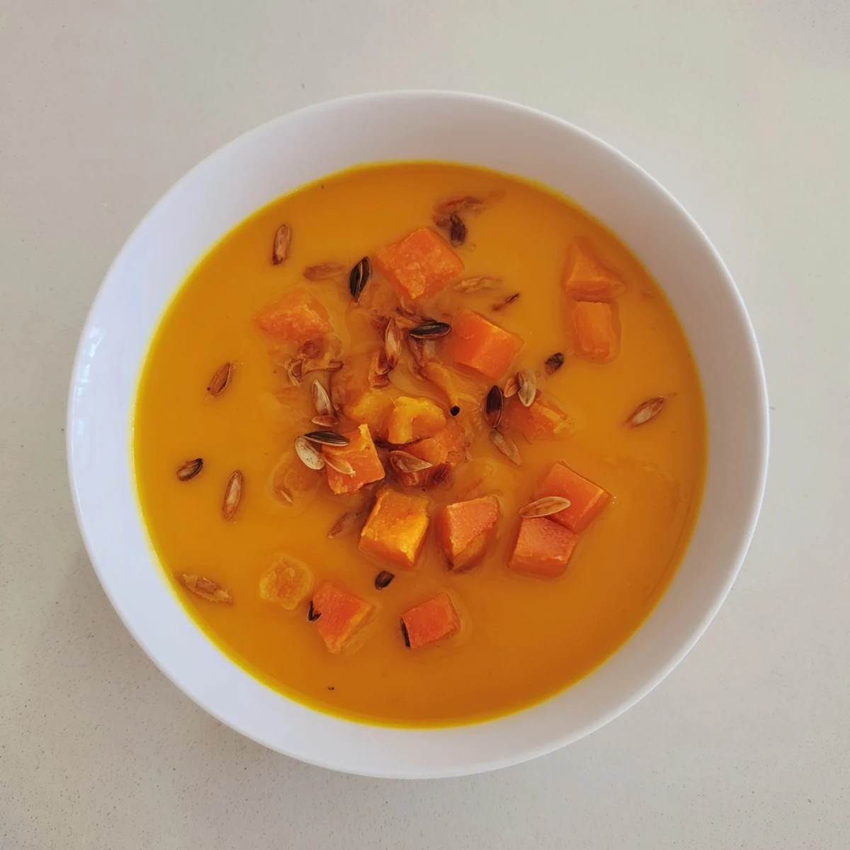 Aromatic creamy roasted pumpkin soup, perfect for fall, garnished with crunchy toasted pepitas.
