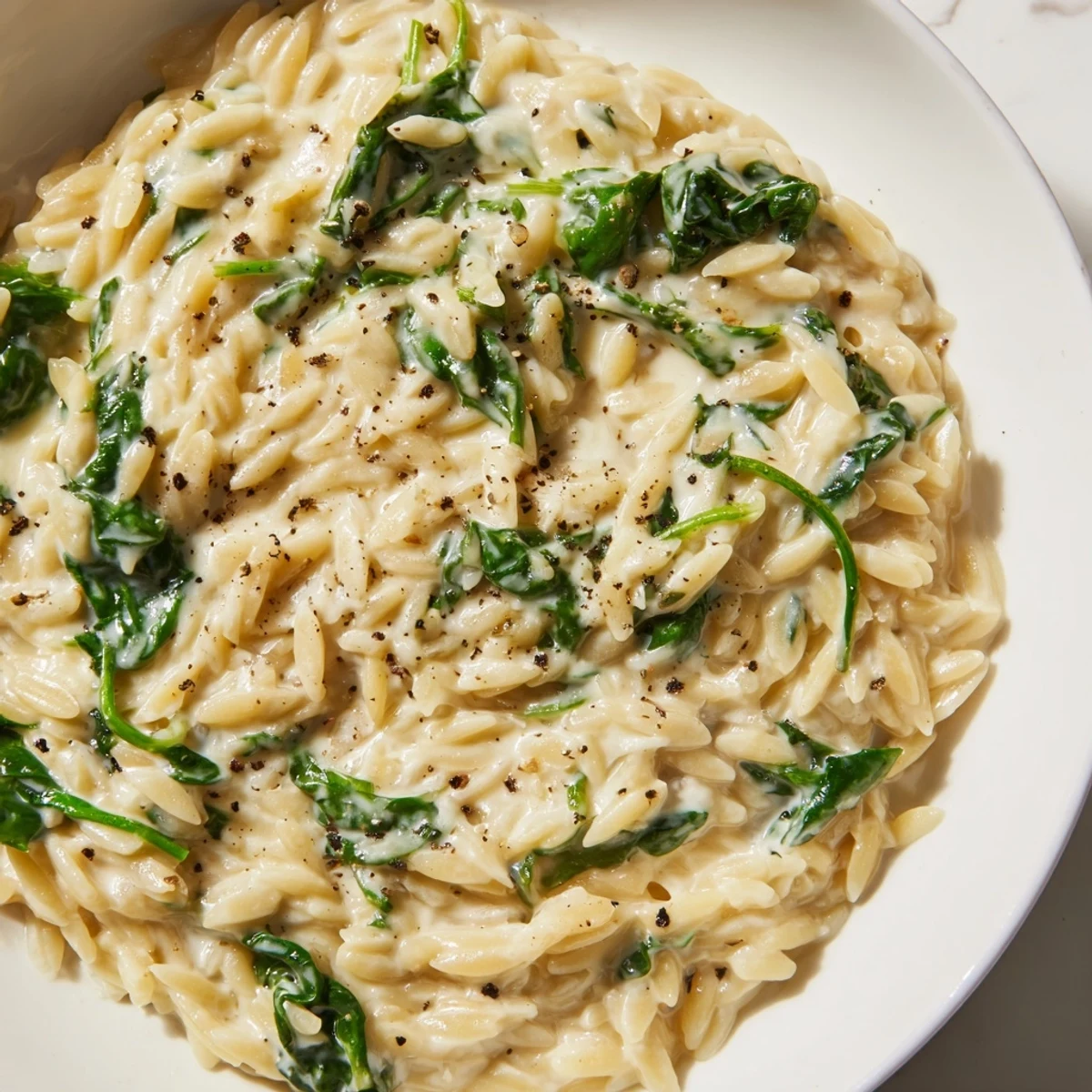 Creamy spinach orzo, a comforting one-pan meal, bubbling gently with spinach and Parmesan cheese.
