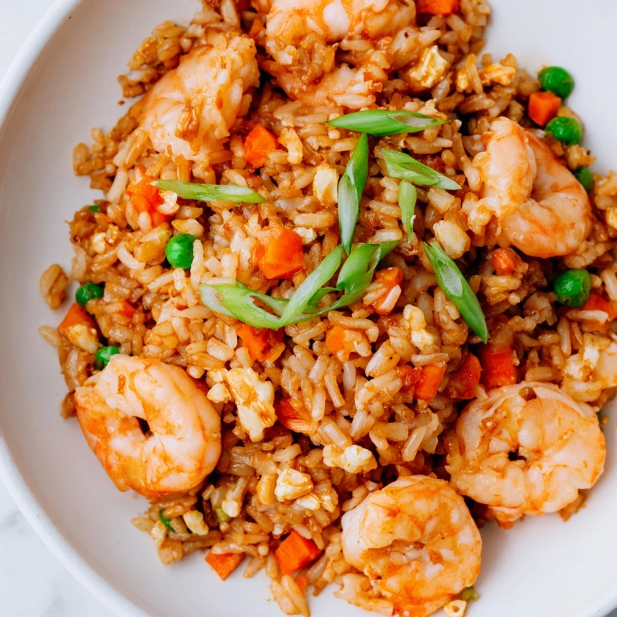 Fragrant garlic shrimp sizzling in a wok, tossed with fluffy jasmine rice, colorful peas, and crisp carrots in savory soy sauce.