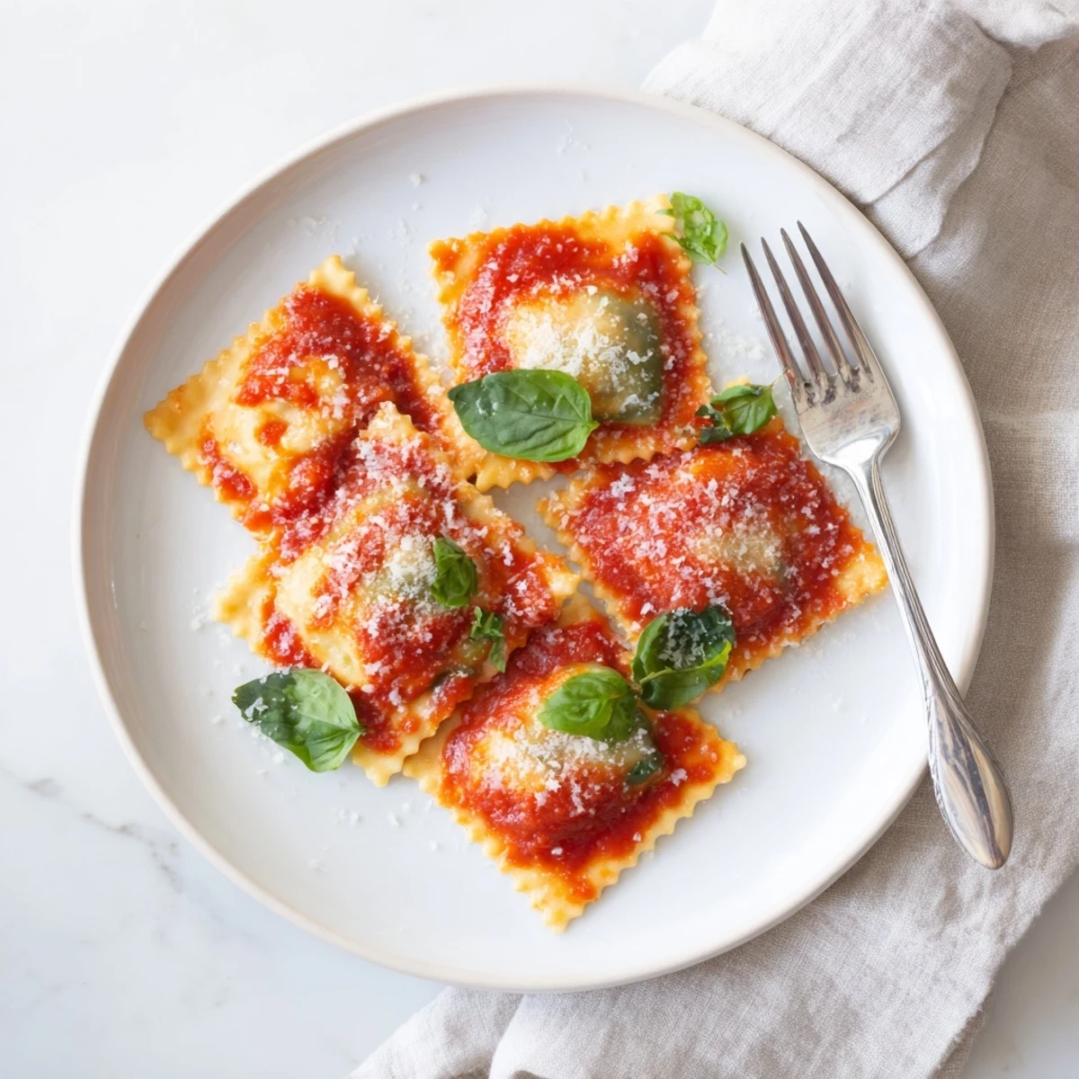 Close-up of golden, homemade Spinach Ricotta Ravioli swimming in a rich, chunky marinara sauce, topped with fresh basil and grated Parmesan.