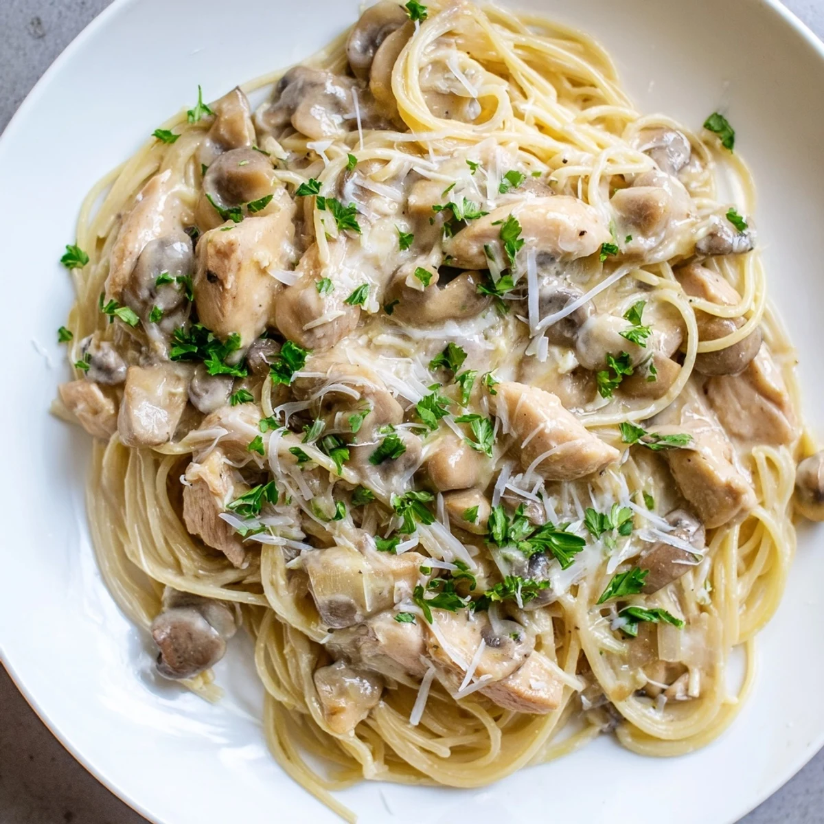 A close-up view of Creamy Mushroom Chicken Spaghettini, highlighting the silky sauce coating the pasta and the sautéed mushrooms' texture.