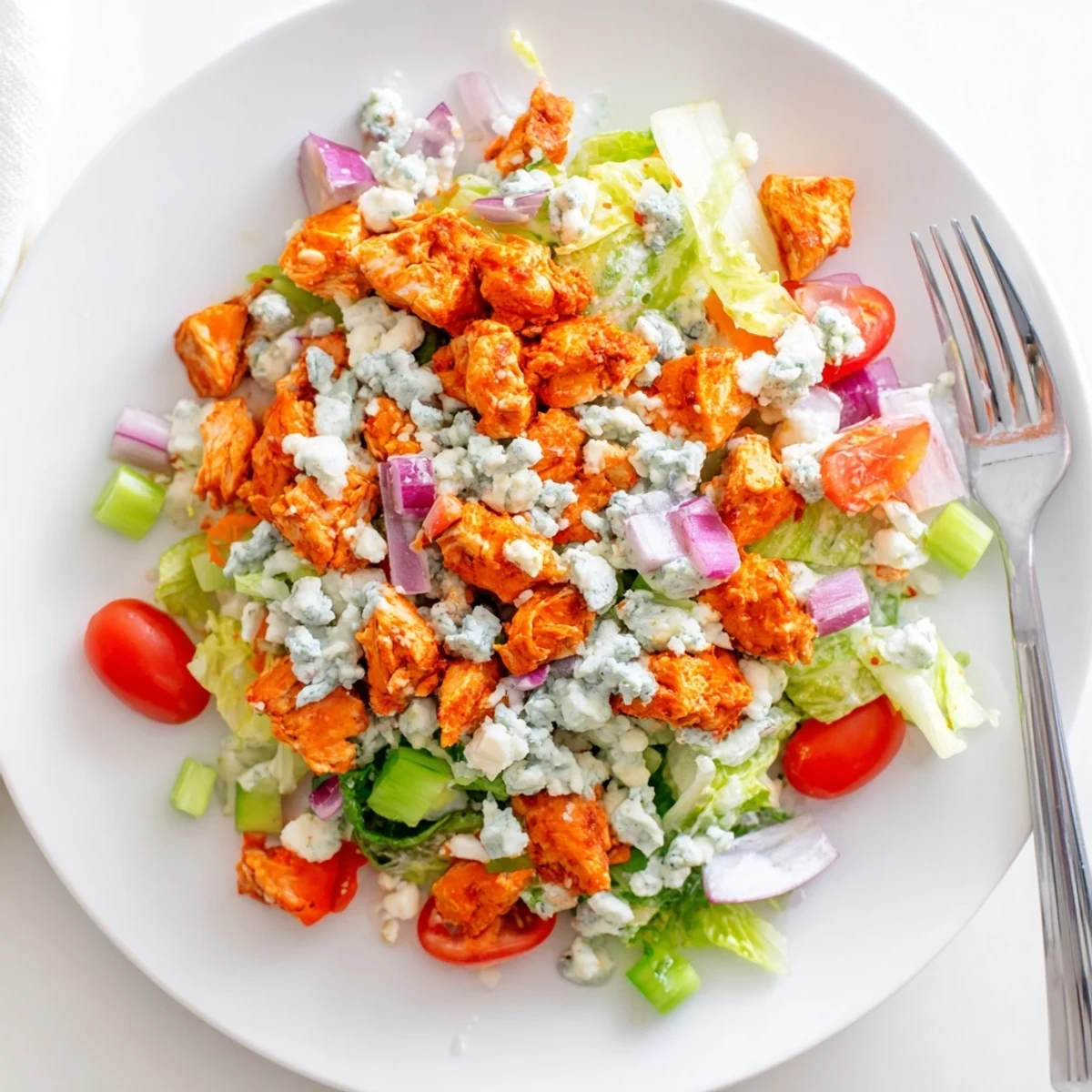 Serving the Buffalo Chicken Chopped Salad drizzled with ranch dressing, topped with blue cheese and cherry tomatoes.