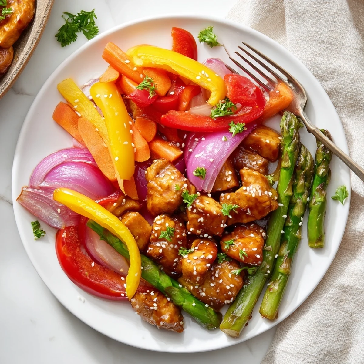 A close view of juicy Sheet Pan Honey Garlic Chicken and crisp veggies glistening with sauce, garnished with fresh parsley and sesame seeds.