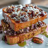 Layered Mexican bread pudding with nuts, dried fruits, and mild cheese, drizzled with cinnamon-spiced piloncillo syrup and baked to perfection.