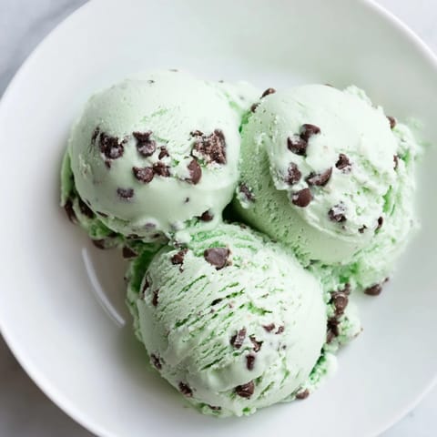 Refreshing swirls of green Mint Chocolate Chip Ice Cream, ready to scoop and enjoy on a warm day.