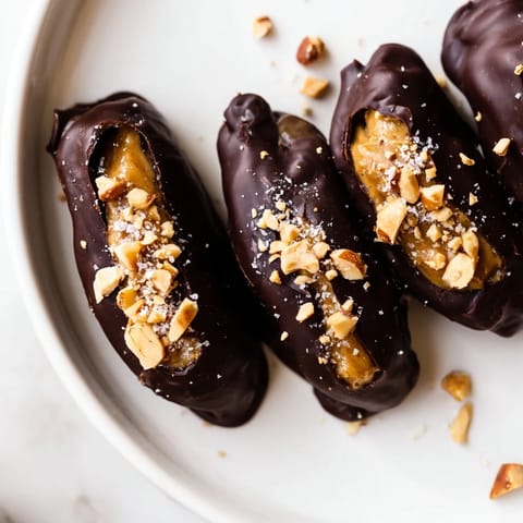 These homemade Chocolate Date Snickers feature a creamy peanut butter filling and chopped peanuts.