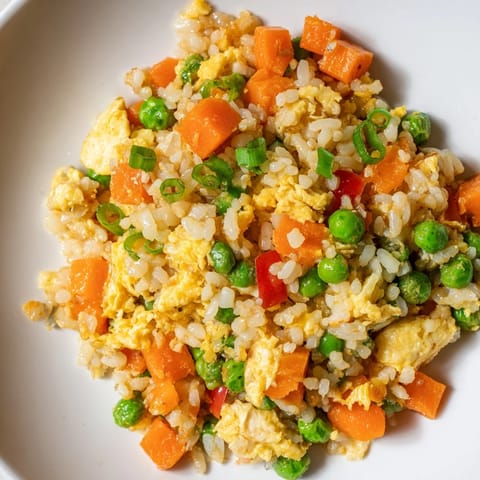 Hearty serving of Egg Fried Rice Classic garnished with fresh green scallions, steaming in a rustic skillet after a quick stir-fry.  
