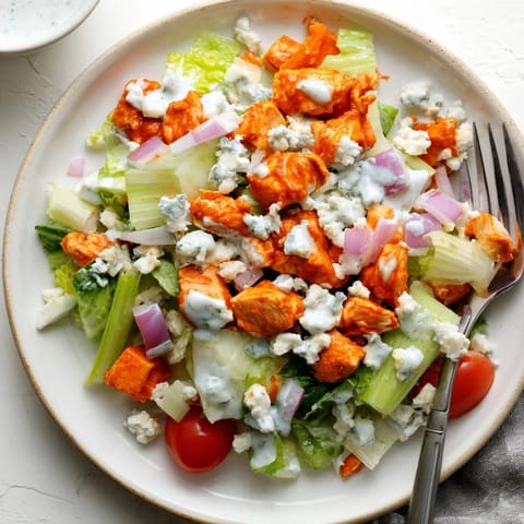 Tossing the spicy buffalo chicken with fresh celery and red onion in a large mixing bowl for a quick lunch.