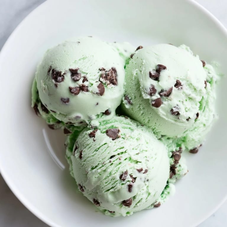 Refreshing swirls of green Mint Chocolate Chip Ice Cream, ready to scoop and enjoy on a warm day.