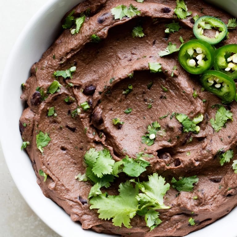 Spicy Black Bean Dip blended smooth with garlic and cumin, paired with colorful vegetable sticks for dipping.