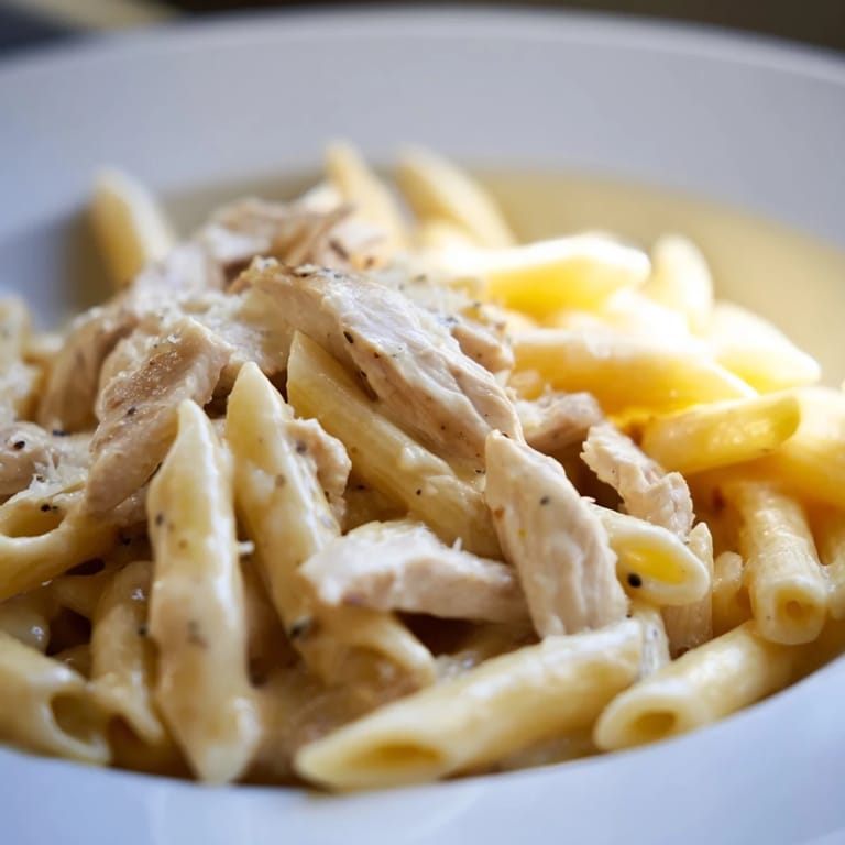 Sizzling skillet of Roasted Garlic Chicken Penne, showcasing savory roasted garlic cloves and creamy sauce clinging to every noodle.