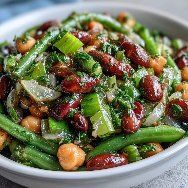Tossing fresh beans, celery, and a tangy dressing in a large bowl for a refreshing, protein-packed Three-Bean Salad.