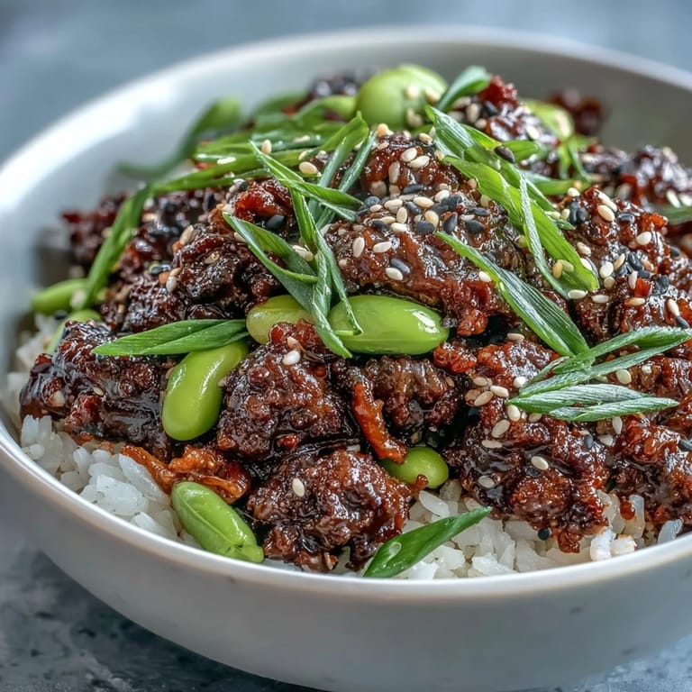 Steaming Korean Ground Beef Bowl topped with kimchi, julienned carrots, cucumber, and sesame seeds.