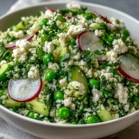 Vibrant Spring Pea and Mint Couscous Salad with fresh herbs and crisp vegetables in a zesty lemon dressing.  